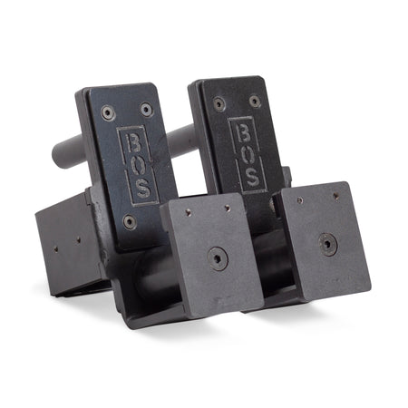 Two Roller J-Cups, in black metal, come engraved with "BOS" for Bells of Steel. These upright brackets are perfect as bench press accessories, featuring flat, rectangular sections with holes for secure mounting or affixing.