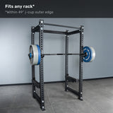 A Bells of Steel Short Rackable Barbell is loaded on j-cups in a black power rack inside a gray room. Text above reads, "Fits any rack* *Within 49” j-cup outer edge—ideal for any home gym.
