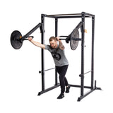 A man in athletic wear uses the Bells of Steel Residential Power Rack (2.3" x 2.3", ⅝" holes), pushing weighted arms to simulate a pressing exercise. Both are isolated on a white background, perfect for any home gym setup.