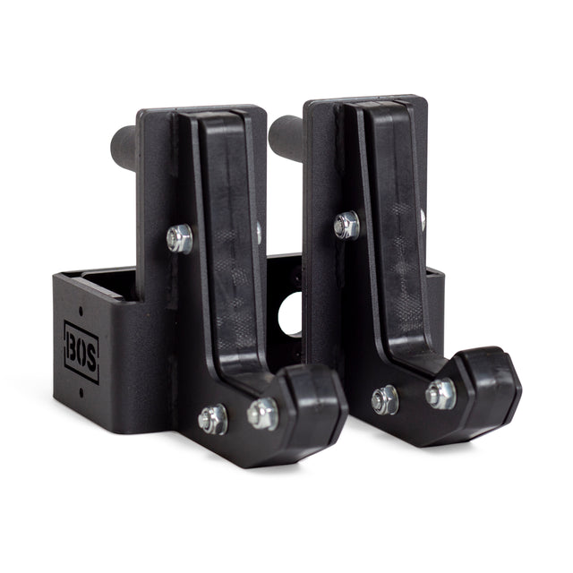 A pair of sturdy L-shaped brackets made from black metal, featuring protective HDPE padding and adjustable screws for wall mounting. The brackets, resembling Sandwich J-Cups by Bells of Steel, are positioned upright and side by side, each displaying the "BOS" logo.