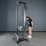 A person grips the Bells of Steel Fat Bar - Single D Handle, attached to a cable machine with stacked weights, building grip strength in a gym with gray walls and a concrete floor.