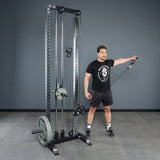 A man stands by a cable machine, holding the Bells of Steel Fat Bar - Single D Handle at shoulder height. Using this fat bar attachment can enhance grip strength during workouts.