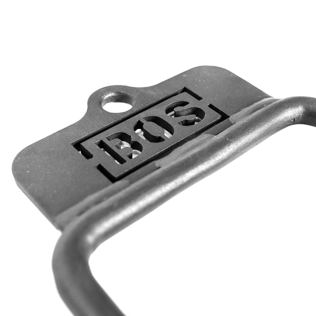 Close-up image of a metal Fat Bar - Single D Handle by Bells of Steel with "BOS" engraved on it. It features a top hole for mounting or cable machine use, emphasizing its industrial style and grip strength potential.