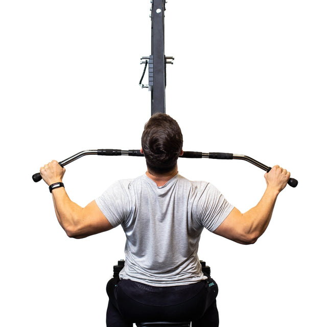 Someone in a gray shirt uses a Bells of Steel Lat Pulldown Bar against a white background, facing away while gripping the bar with both hands and elbows bent.