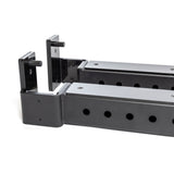 Two black metal Bells of Steel Flip-Down Safeties gym rack attachments with multiple adjustment holes and hooks are shown close-up on a white background, designed for training safety and to support weights or bars on a power rack.