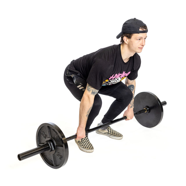 A person wearing a black t-shirt, black pants, and a cap is preparing to lift the Bells of Steel Short Utility Barbell with weights. They are crouched in a starting position, looking ahead, on a white background.