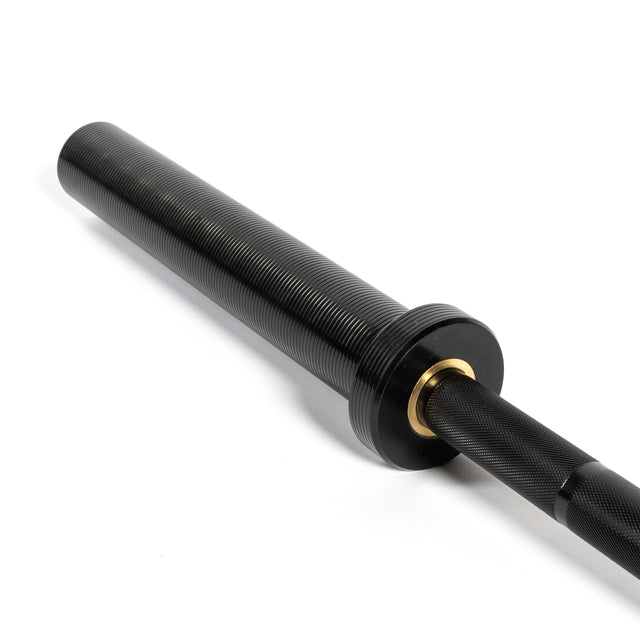 Close-up of a Short Utility Barbell sleeve from Bells of Steel, showcasing a black ribbed texture with a smooth, shiny finish. The metal includes a golden ring detail near the end, offering a sleek and modern appearance perfect for Olympic lifts. The barbell is positioned diagonally on a white background.