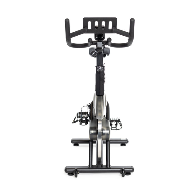 The Bells of Steel Blitz Indoor Cycling Bike, shown from the front, features magnetic resistance and adjustable handlebars. This stylish black bike with silver accents includes a digital console and pedals against a plain white background.