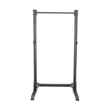 The Bells of Steel Manticore Squat Stand Builder is a freestanding black metal rack with a pull-up bar, adjustable slots for a barbell, and a sturdy rectangular base for stability.