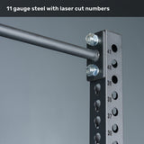 Close-up of the Bells of Steel Manticore Squat Stand - Prebuilt, featuring robust black 3" x 3" 11-gauge steel uprights with precise laser-cut numbered 1" holes, heavy-duty bolts, and a sturdy horizontal bar—perfect for any home gym. Text above reads: "11 gauge steel with laser cut numbers.