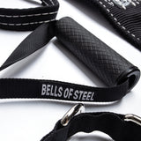 Close-up of the Bells of Steel Suspension Spotter Straps and Bodyweight System for home gym training, featuring sturdy metal clips, textured handles, detailed stitching, and "Bells of Steel" branding in white.