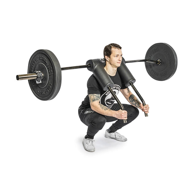 A man in a black outfit performs a versatile squat exercise with the Bells of Steel Safety Squat Bar - The SS4, featuring an ergonomic shoulder pad. The bar is loaded with large weights on each side.