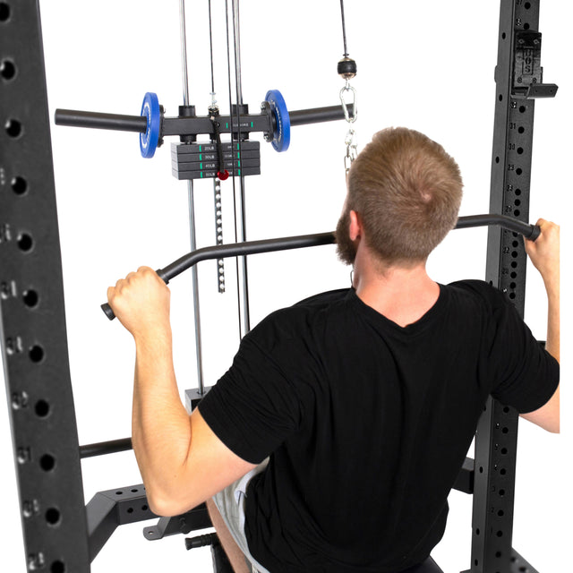 A short-haired, bearded individual is performing a seated lat pulldown with the Bells of Steel Lat Pulldown & Low Row Rack Attachment - Hydra & Manticore, using a wide bar and Olympic Weights in their squat rack setup.