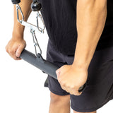 A person in black grips the Bells of Steel Fat Bar - Straight Handle Bar on a cable machine, preparing for a strength exercise like a tricep pushdown to boost grip strength.
