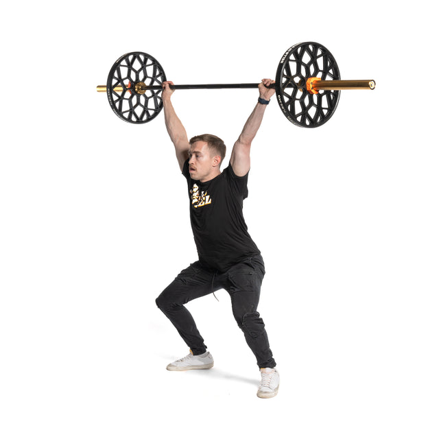 Wearing athletic gear, a person executes an overhead squat using Bells of Steel's Technique Plates - 5 Lbs (Pair), recognized for their unique open circular designs. The white backdrop highlights the movement, ideal for a home gym.