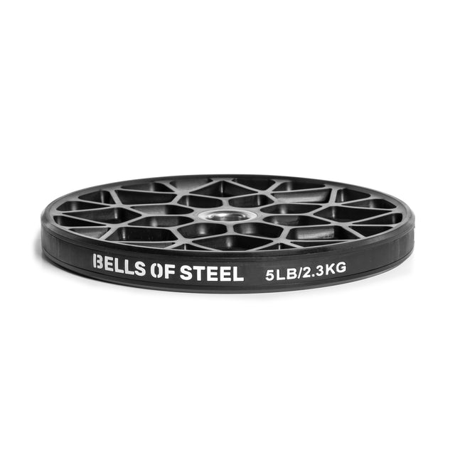 A black weight plate with a web-like design, labeled "BELLS OF STEEL" and "5LB/2.3KG," stands upright against a white background. Ideal for any home gym needing versatile Technique Plates - 5 Lbs (Pair) by Bells of Steel.