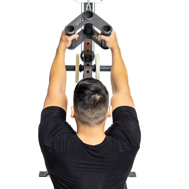 A person with short dark hair in a black T-shirt uses the Bells of Steel Fat Bar - T-Bar Row Cable Attachment. Seen from behind, they manage thick handles and lean forward slightly, performing a back workout that boosts grip strength.