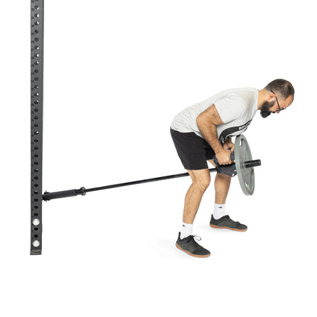 A person in a gray shirt and black shorts expertly performs a Fat Bar T-Bar Row exercise using the Bells of Steel Fat Bar - T-Bar Row Cable Attachment, showcasing impressive grip strength at a landmine station against a pristine white background.