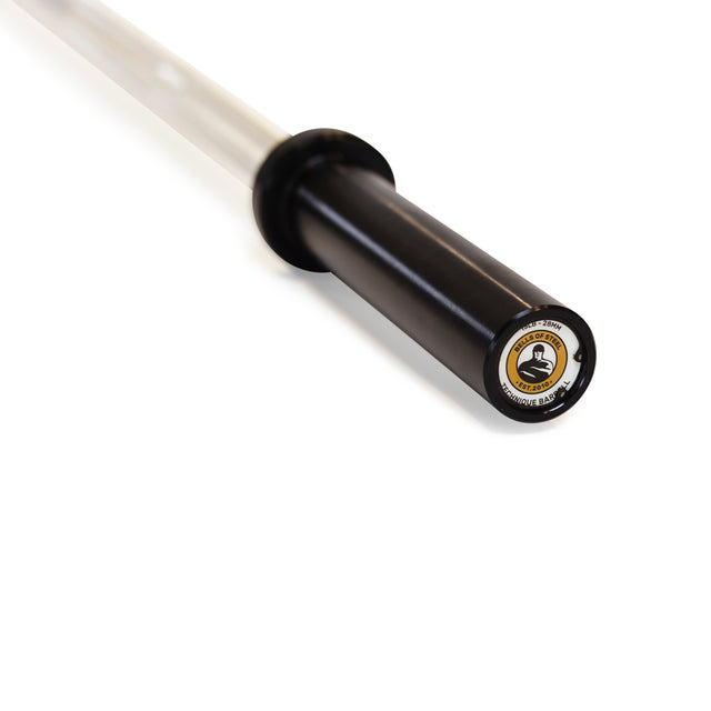 Close-up of the black sleeve of the Bells of Steel Aluminum Technique Barbell with a gold and white logo, crafted from high-quality materials, extending out of frame against a white background.