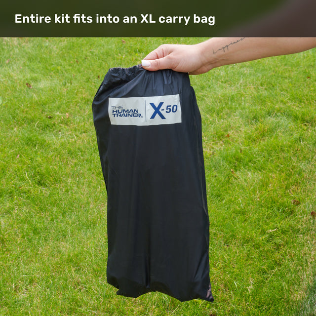 A hand holds a black Bells of Steel XL carry bag on green grass, with text above reading, “Entire Agility Ladder and Leg Cord Bundle fits into an XL carry bag.”.