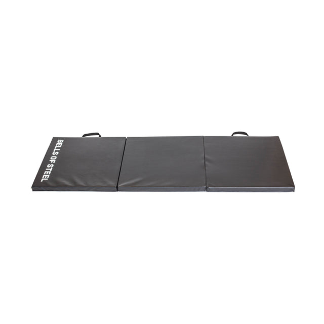 A black, foldable exercise mat by Bells of Steel is divided into three sections with visible seams, boasting two top-edge handles. Ideal for Turkish Get-Ups to boost functional strength, it features the brand name in white on the top left corner.