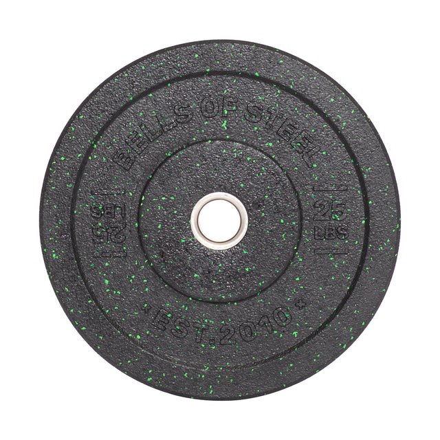 A round, black Crumb Bumper Plate by Bells of Steel, adorned with green speckles and marked "25 lbs" & "EST 2010," features a central barbell hole and durable stainless steel insert ring.