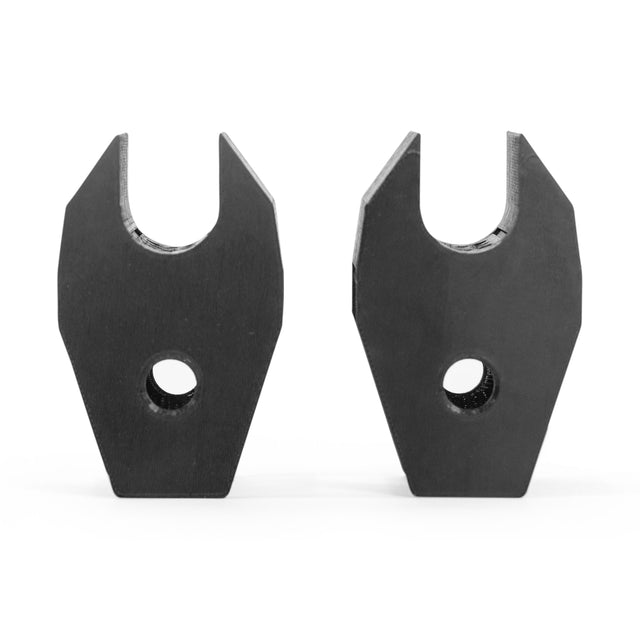 On a white background, the Above Rack Barbell Holder by Bells of Steel features two black metal brackets with angled tops and central circular holes standing upright. Resembling sturdy components of a power rack, they have similar geometric shapes ideal for supporting or connecting elements in a fitness setup.