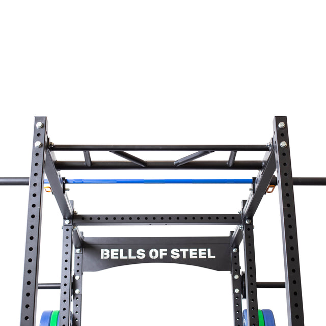 A durable metal frame branded as "Bells of Steel" is set against a white backdrop. It includes the Above Rack Barbell Holder and a versatile pull-up station, along with multiple attachments for all-encompassing strength training.