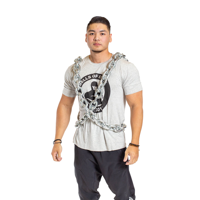 A man models the Bells of Steel Chain Weight Vest, draped over his shoulders and torso, wearing a light gray t-shirt and black pants against a plain white background—ideal for strength training visuals.