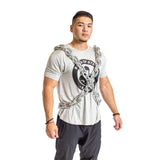 A man stands confidently in a Bells of Steel Chain Weight Vest, with weighted chains forming an X across his gray t-shirt and black pants. The background is white.