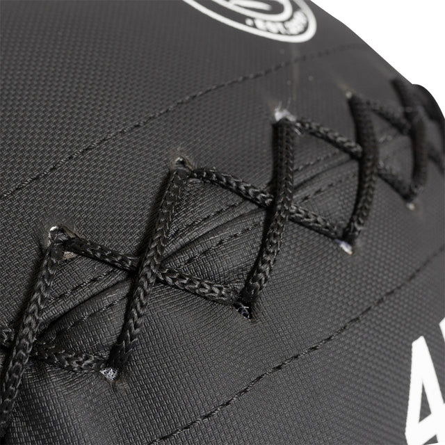 Close-up of triple stitching on dark leather reminiscent of Kevlar's protective touch, inspired by the intricate pattern and texture on Bells of Steel medicine balls.