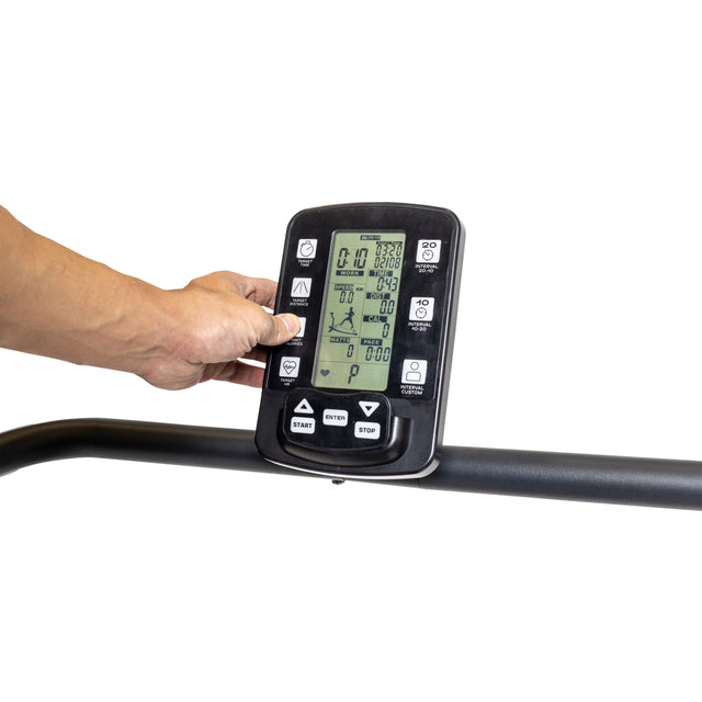 A person interacts with a Bells of Steel Wooden Residential Manual Treadmill control panel displaying settings and metrics. The handlebar with high-strength nylon slats is visible beneath. The background is plain white.