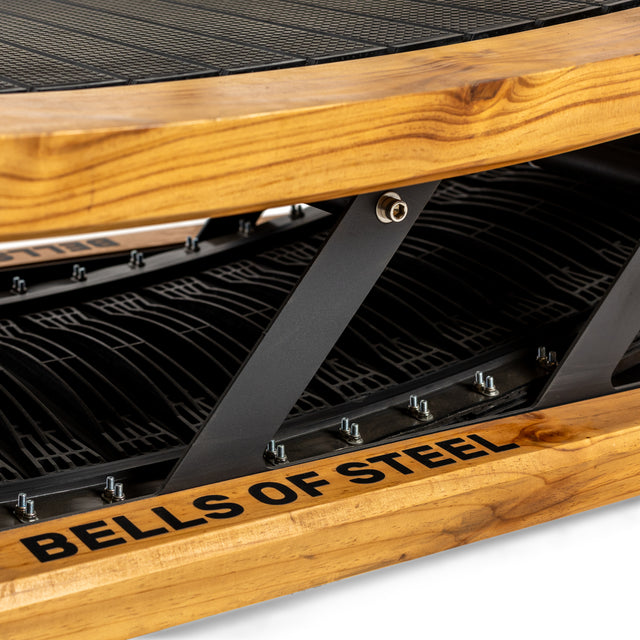 Close-up of the Wooden Residential Manual Treadmill by Bells of Steel, featuring a wood-textured frame, compact design, black mesh running surface, and visible metal bolts.