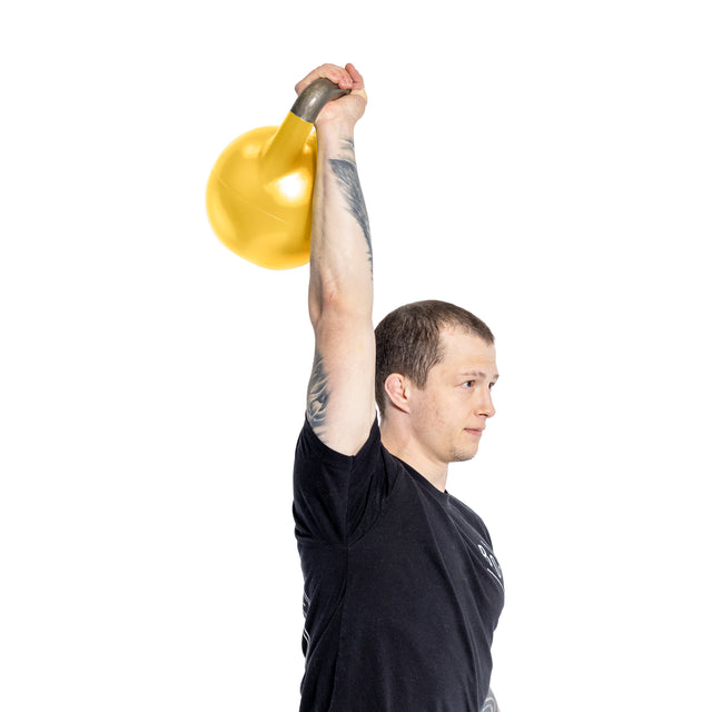 Against a plain white background, an individual in a black t-shirt with tattoos lifts a Bells of Steel's Adjustable Competition Kettlebell, showcasing its vibrant yellow design.