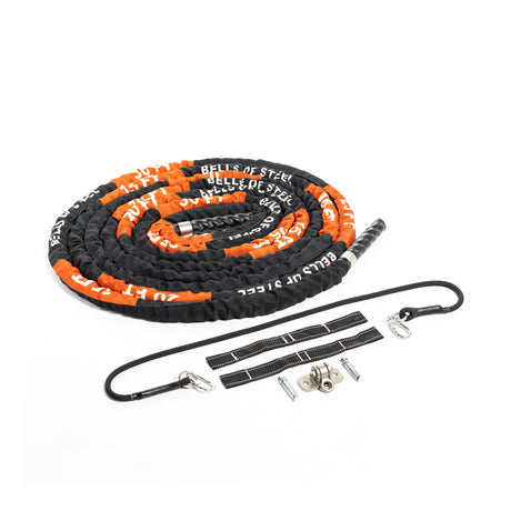 A Bells of Steel battle rope, coiled in black and orange, is displayed with metal clips and mounting hardware on a white background, ideal for an intense conditioning workout.