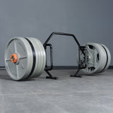 A Bells of Steel Open Trap Bar / Hex Bar with large gray plates sits on a gray tiled floor against a dark gray wall—ideal for home gym deadlift workouts.
