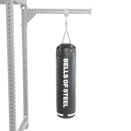 A black Heavy Bag Set from Bells of Steel hangs by chains from a metal frame resembling a power rack, set against a white background.