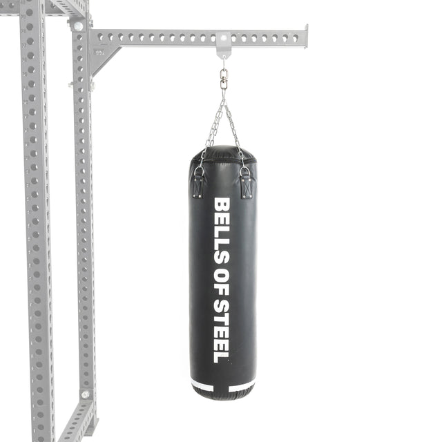 A black Heavy Bag Set from Bells of Steel hangs by chains from a metal frame resembling a power rack, set against a white background.