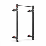 The Bells of Steel Roc Foldable 2 Post Cage Builder features a black metal squat rack with two upright beams, a pull-up bar, adjustable safety arms with red handles, and customizable ⅝" holes. It's perfect for any home gym and is set against a white background.