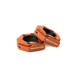 Two orange, hexagonal Magnetic Clamp Collars by Bells of Steel with black interiors and "BELLS OF STEEL" printed on the side, displayed on a white background.