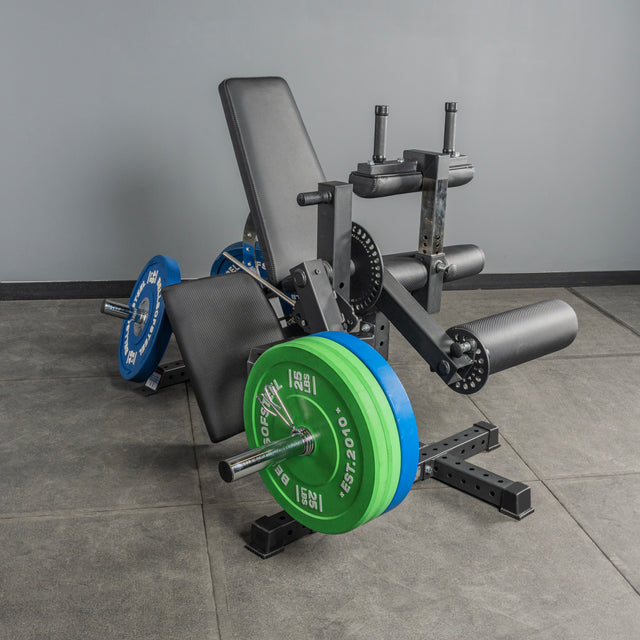 The Bells of Steel Legacy Leg Extension / Hamstring Curl Machine - Plate Loaded is set on a gray floor against a plain gray wall in a home gym, featuring adjustable settings for leg exercises.