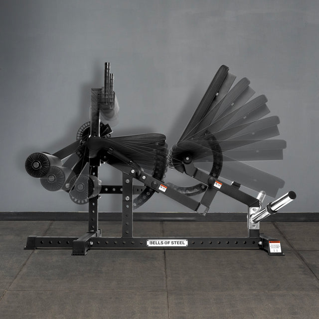 The Bells of Steel Legacy Leg Extension / Hamstring Curl Machine - Plate Loaded is shown in black with an adjustable backrest at multiple angles, standing on a mat against a gray wall—perfect for any home gym setup.