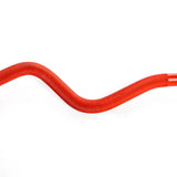 A 100% RAW Competition Curl Bar by Bells of Steel, a red, wavy metal tube with a textured pattern, rests against a white background, creating an interesting visual contrast.