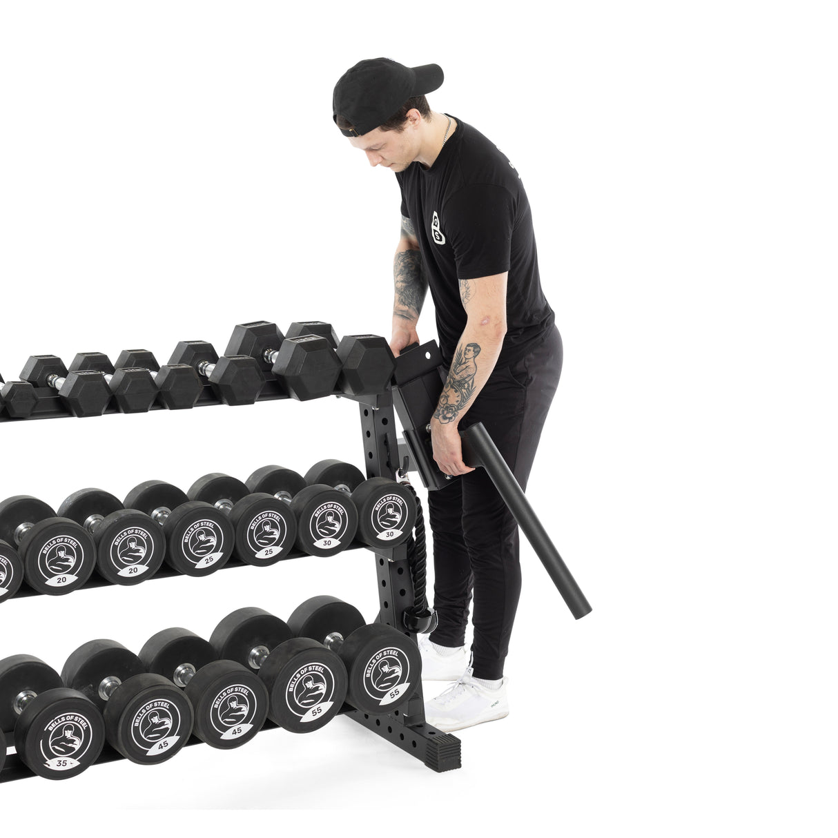 A person in black attire and a cap organizes hex dumbbells on the Bells of Steel Residential Dumbbell Rack, featuring multiple rows with various weights for a perfect home gym setup. The plain white background highlights the sleek organization of this equipment.