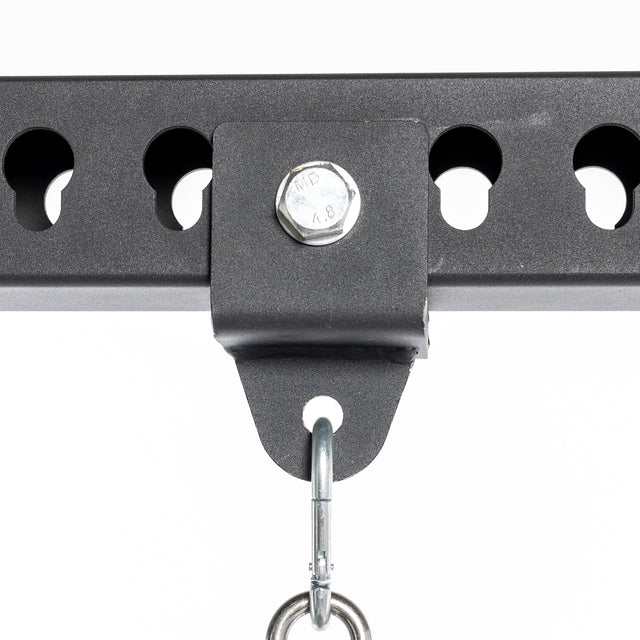 Close-up of the Bells of Steel Utility Shackle Rack Attachment: a black metal bracket bolted to a horizontal perforated beam, perfect for home gyms. A shackle hangs from the bracket, attached to a circular ring. The plain white background highlights the rack attachment's details.