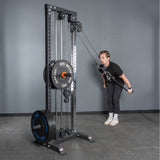 Wearing workout clothes, a person uses the Bells of Steel Extra Long Tricep Rope Extension (137cm) for tricep pushdowns, standing on a gym floor against a gray wall.